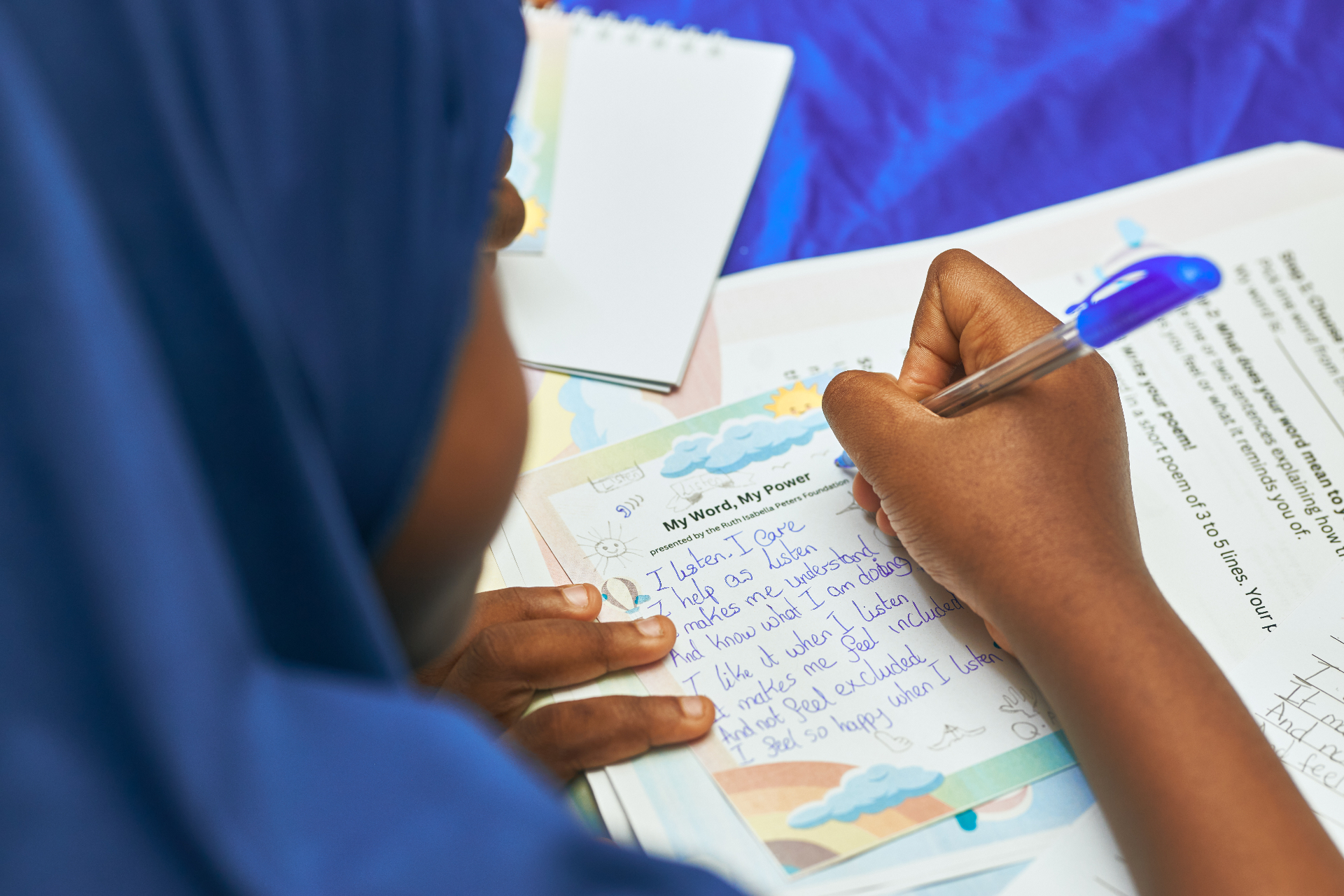 Close-up of a child writing 'I listen, I care' on a foundation worksheet