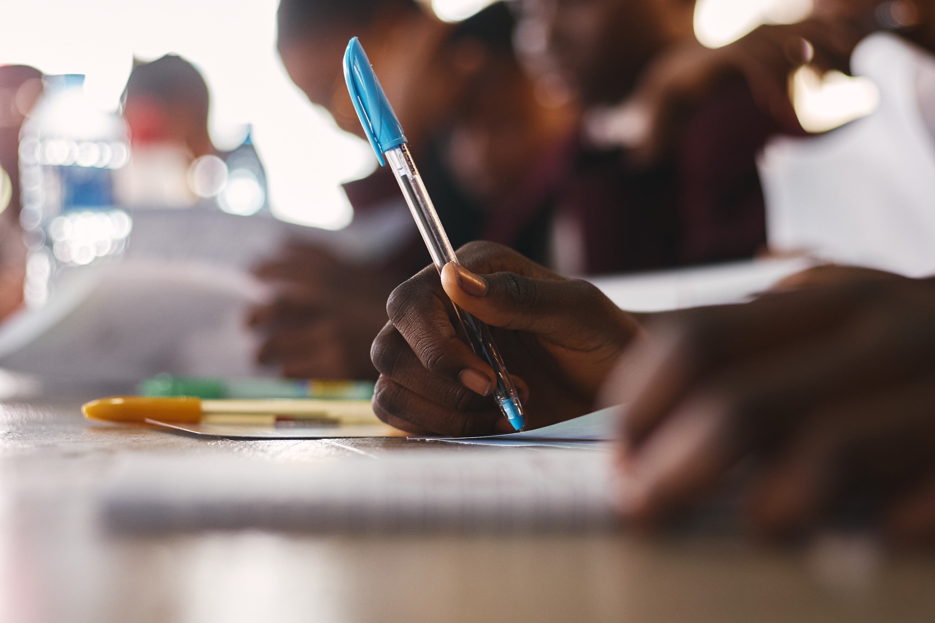 Close-up of a child's hands writing in a notebook during a workshop